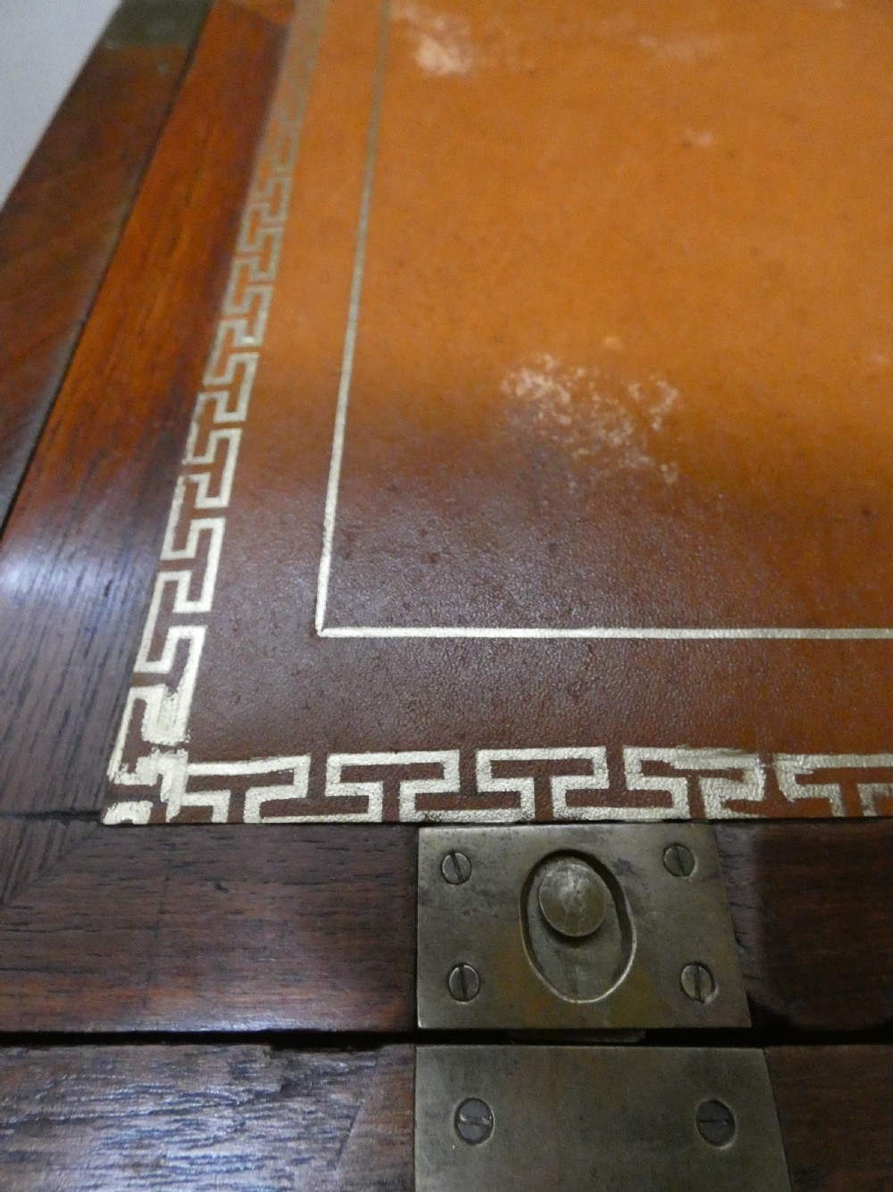 An antique teak campaign secretaire chest featuring brass corner mounts, flush drawer handles, carrying handles, and a drop-front slanted leather writing desk. View VII