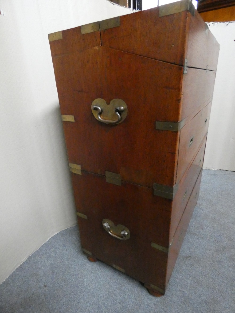 An antique teak campaign secretaire chest featuring brass corner mounts, flush drawer handles, carrying handles, and a drop-front slanted leather writing desk. View IX