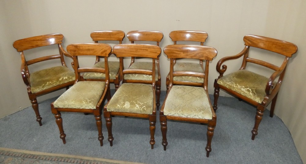 A set of eight antique mahogany dining chairs featuring curved bar backs, turned front legs, and mustard patterned fabric seats. View III