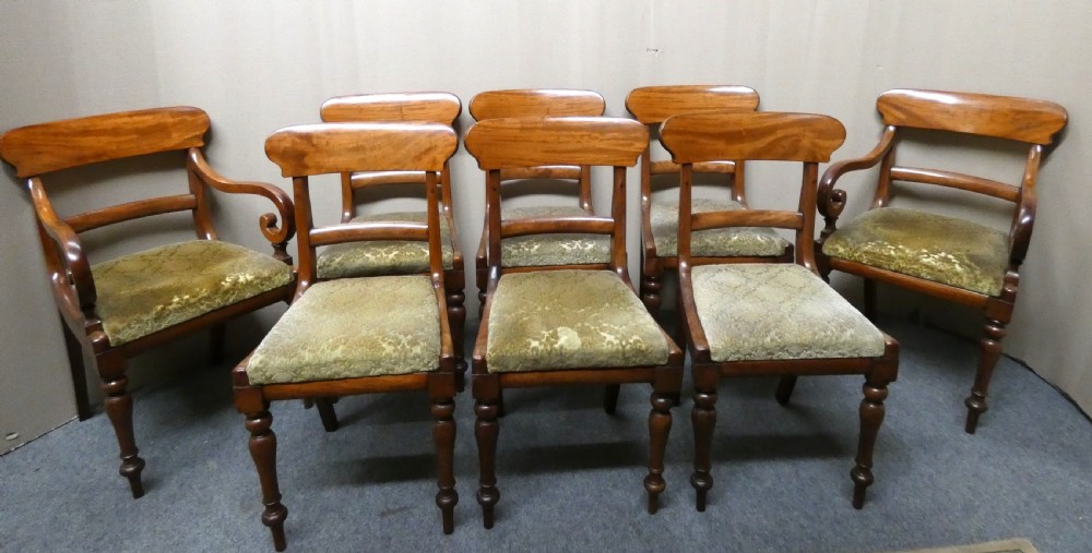 A set of eight antique mahogany dining chairs featuring curved bar backs, turned front legs, and mustard patterned fabric seats. View VIII