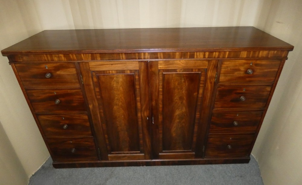 A Georgian mahogany low linen press featuring two central panelled doors flanked by eight side drawers with turned wooden knobs. View II