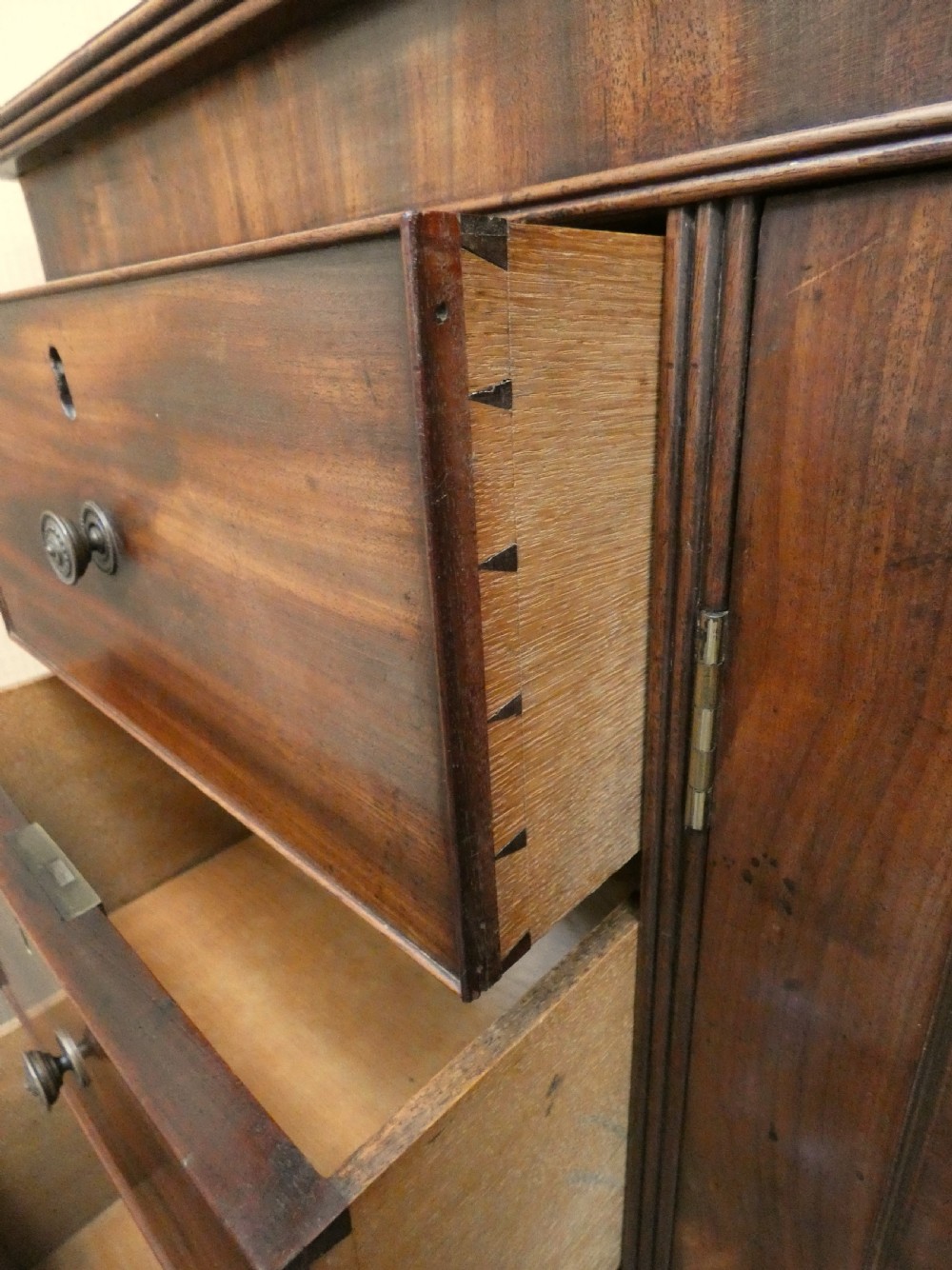 A Georgian mahogany low linen press featuring two central panelled doors flanked by eight side drawers with turned wooden knobs. View VI