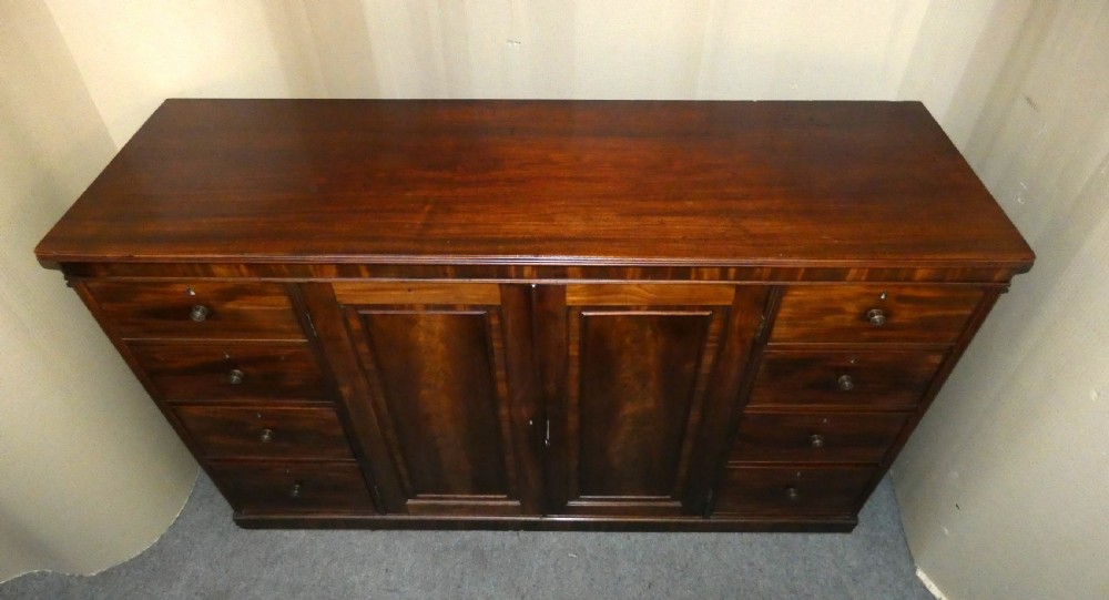 A Georgian mahogany low linen press featuring two central panelled doors flanked by eight side drawers with turned wooden knobs. View VIII