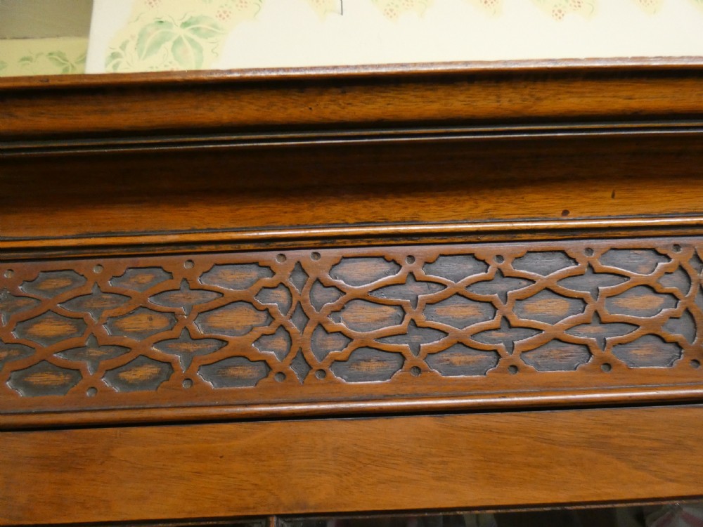 An antique mahogany bookcase featuring two astragal glazed doors, a carved fretwork frieze, and cabriole legs with claw and ball feet. View VI