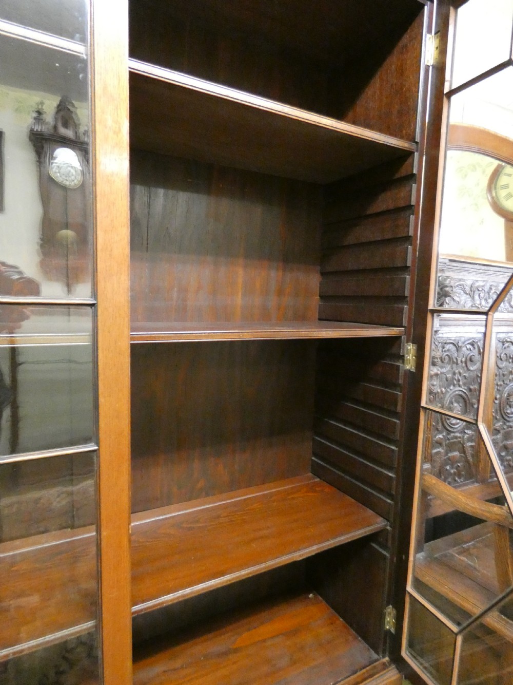 An antique mahogany bookcase featuring two astragal glazed doors, a carved fretwork frieze, and cabriole legs with claw and ball feet. View VIII