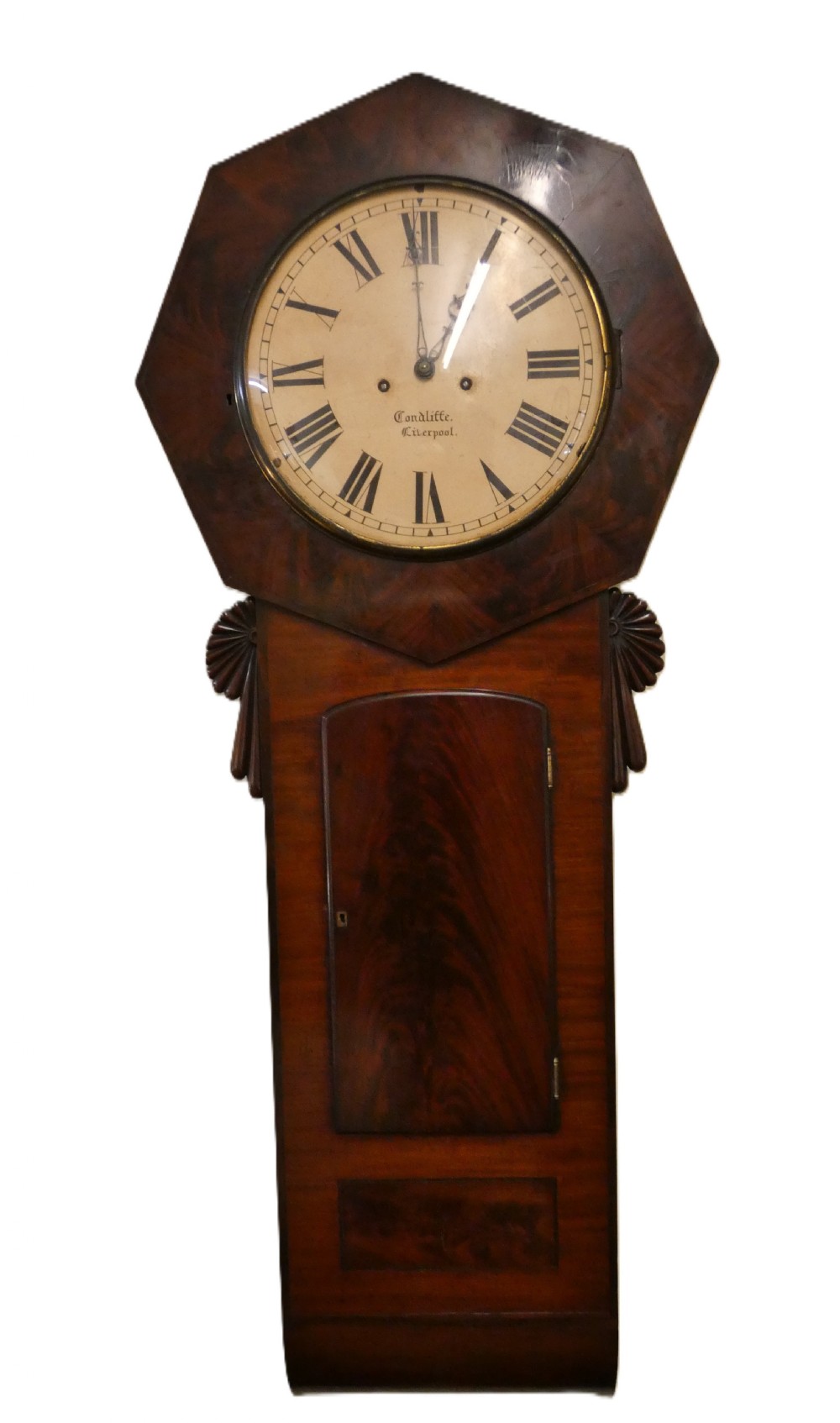 An antique mahogany tavern wall clock featuring an octagonal dial surround, carved side ears, and a long rectangular trunk with a flame mahogany door. View XI