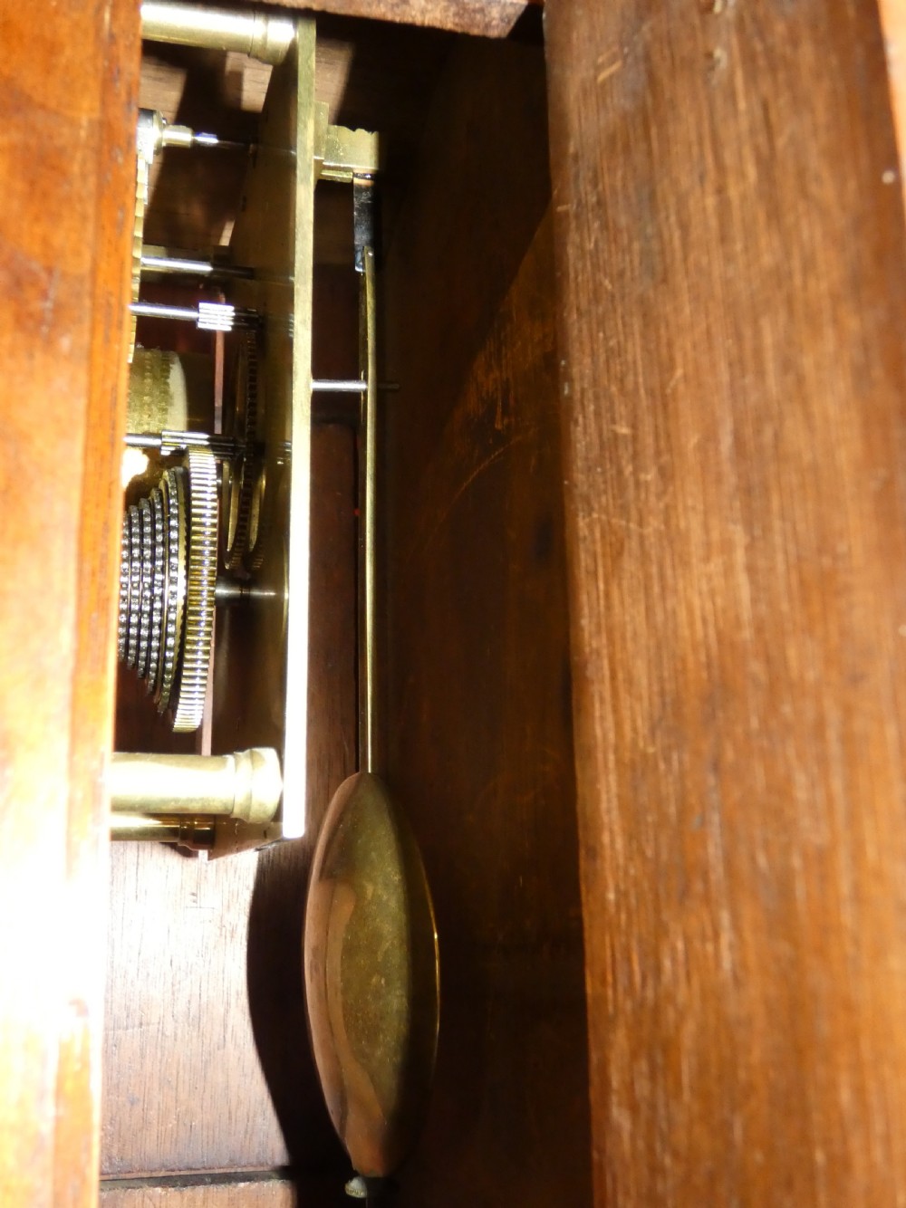 A carved walnut bracket clock featuring scrollwork ornamentation, a wall-mounting bracket, and a white dial displaying Roman numerals with the maker name Connell London. View VII
