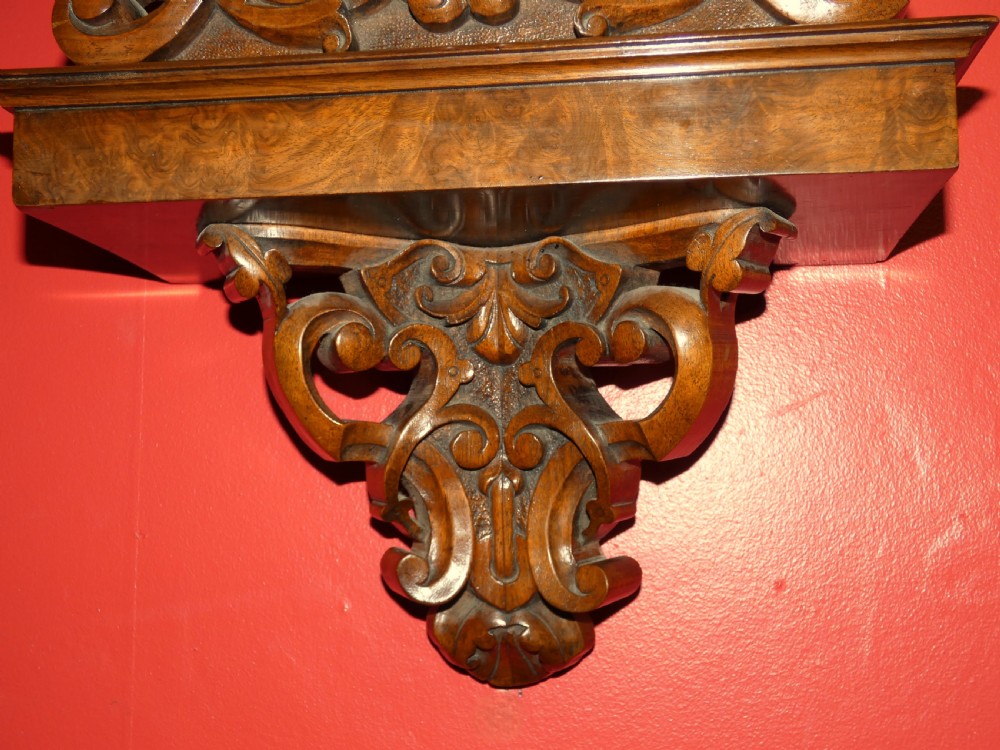 A carved walnut bracket clock featuring scrollwork ornamentation, a wall-mounting bracket, and a white dial displaying Roman numerals with the maker name Connell London. View VIII