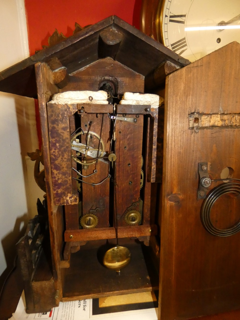 Hand-carved dark wood Black Forest cuckoo clock featuring intricate vine leaf ornamentation around a circular dial with Roman numerals and a cuckoo bird aperture. View VIII