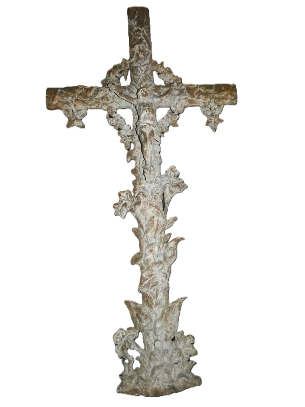 A weathered cast iron grave crucifix featuring detailed foliate work along the vertical beam and the figure of Christ in relief against a distressed grey finish.