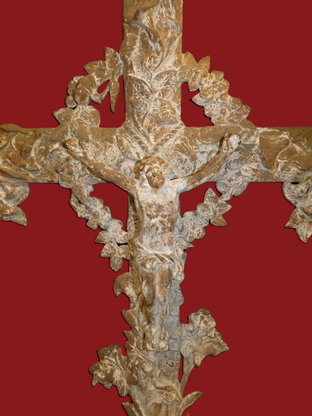 A weathered cast iron grave crucifix featuring detailed foliate work along the vertical beam and the figure of Christ in relief against a distressed grey finish. View II