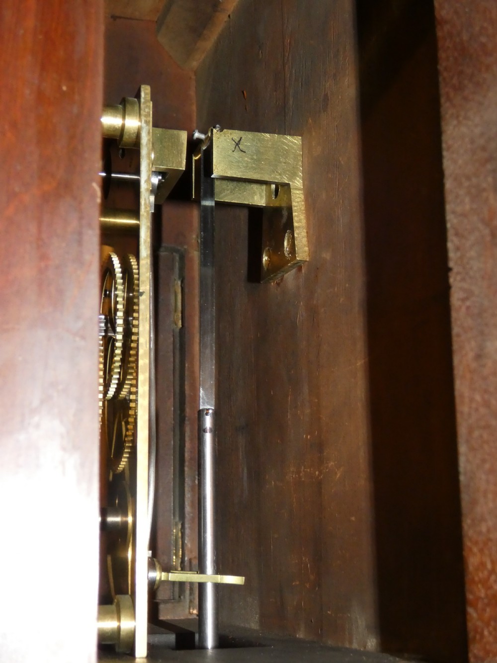 A tall Victorian mahogany regulator wall clock featuring a circular white dial with Roman numerals and a long rectangular wooden trunk. View VII