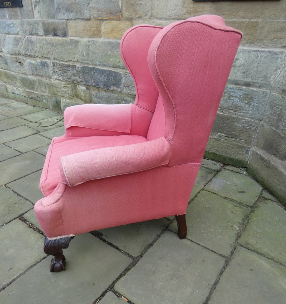 A 19th-century wingback armchair upholstered in rose pink fabric with carved mahogany cabriole front legs resting on ball-and-claw feet. View VII