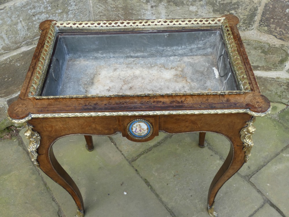 A French Louis XV style burr walnut jardiniere table with cabriole legs, ormolu mounts, a central porcelain plaque, and a brass gallery rim. View III