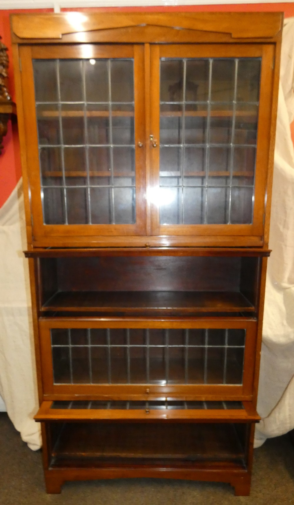 An Edwardian mahogany four-section stacking bookcase featuring leaded glass panel doors and small wooden knobs. View IV