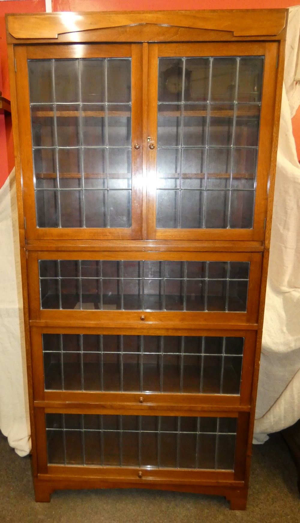 An Edwardian mahogany four-section stacking bookcase featuring leaded glass panel doors and small wooden knobs. View VIII