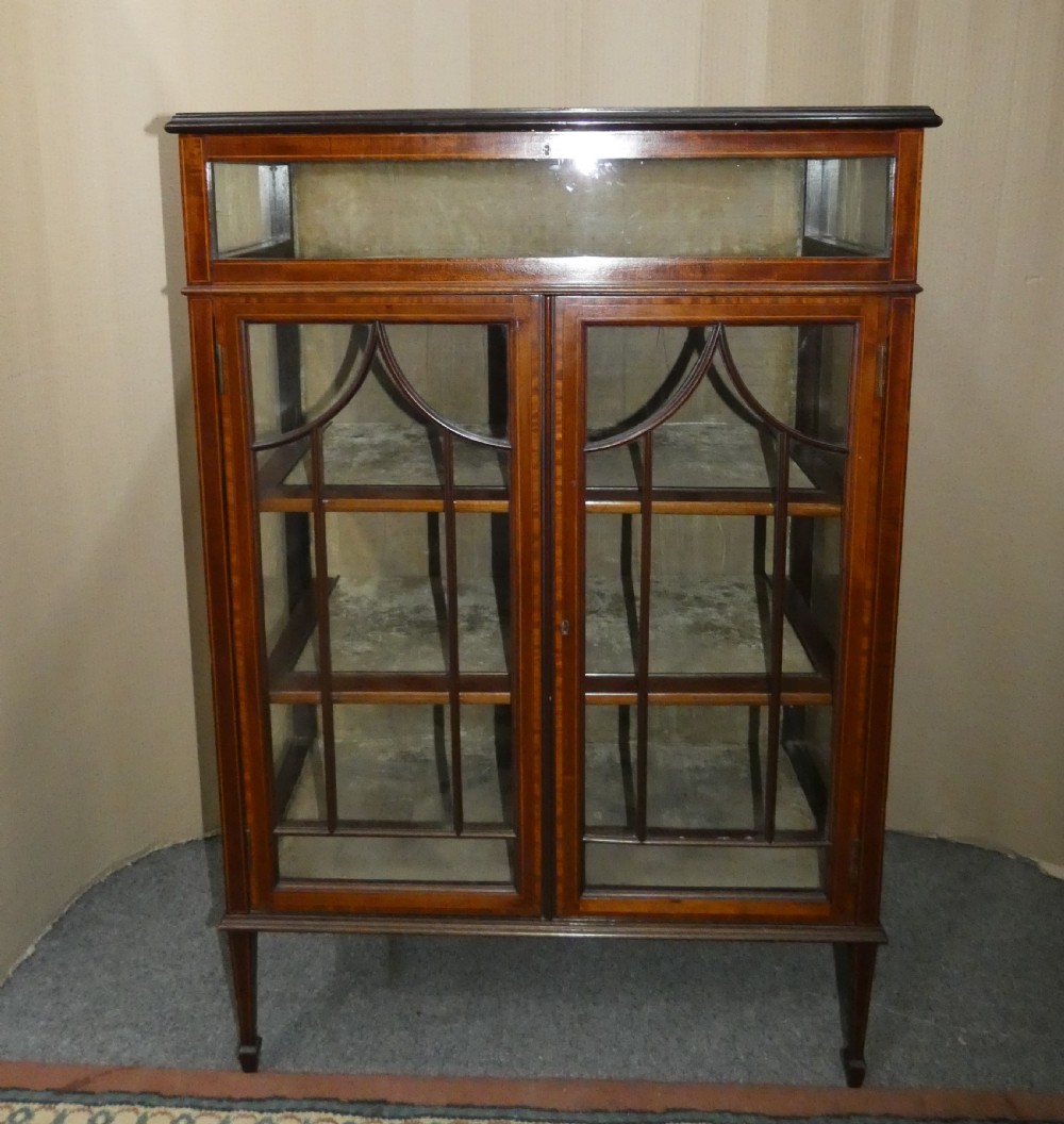 An inlaid mahogany bijouterie cabinet featuring a glass display section at the top, two glazed doors with astragal bars below, and tapered legs.