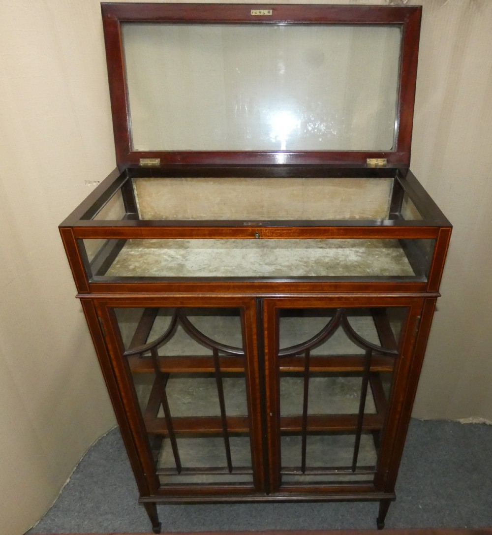 An inlaid mahogany bijouterie cabinet featuring a glass display section at the top, two glazed doors with astragal bars below, and tapered legs. View IV