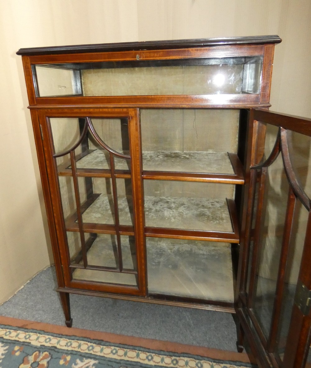 An inlaid mahogany bijouterie cabinet featuring a glass display section at the top, two glazed doors with astragal bars below, and tapered legs. View V