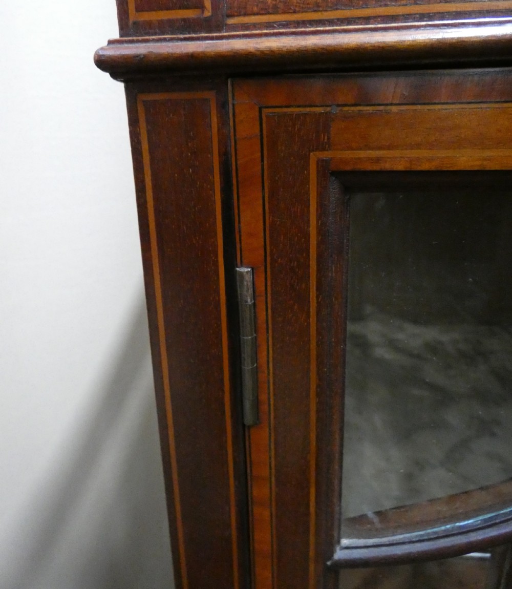 An inlaid mahogany bijouterie cabinet featuring a glass display section at the top, two glazed doors with astragal bars below, and tapered legs. View VI