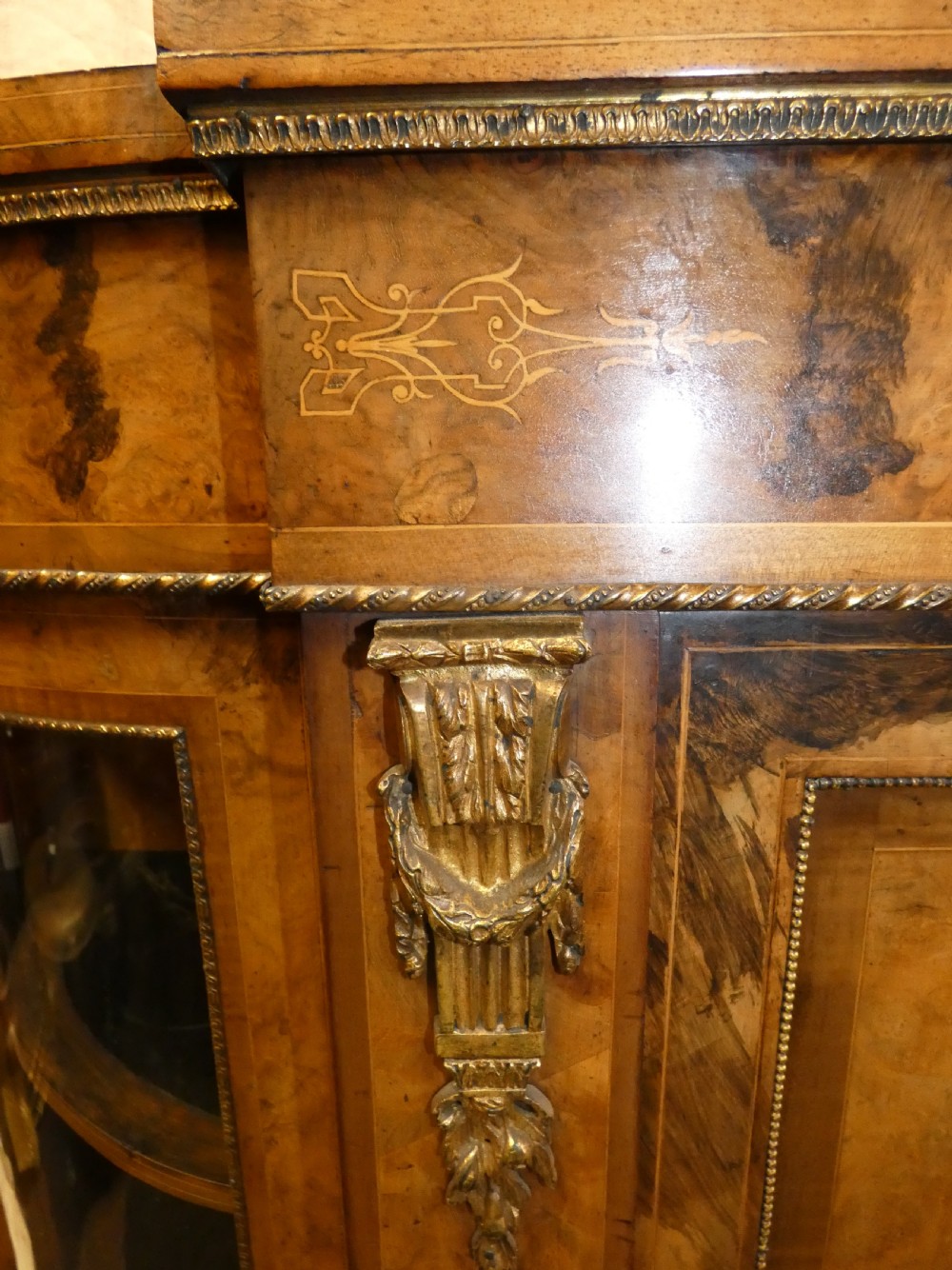 A Victorian burr walnut credenza featuring central wooden doors with marquetry urn motifs, flanked by curved glazed side compartments and gilt bronze mounts. View III