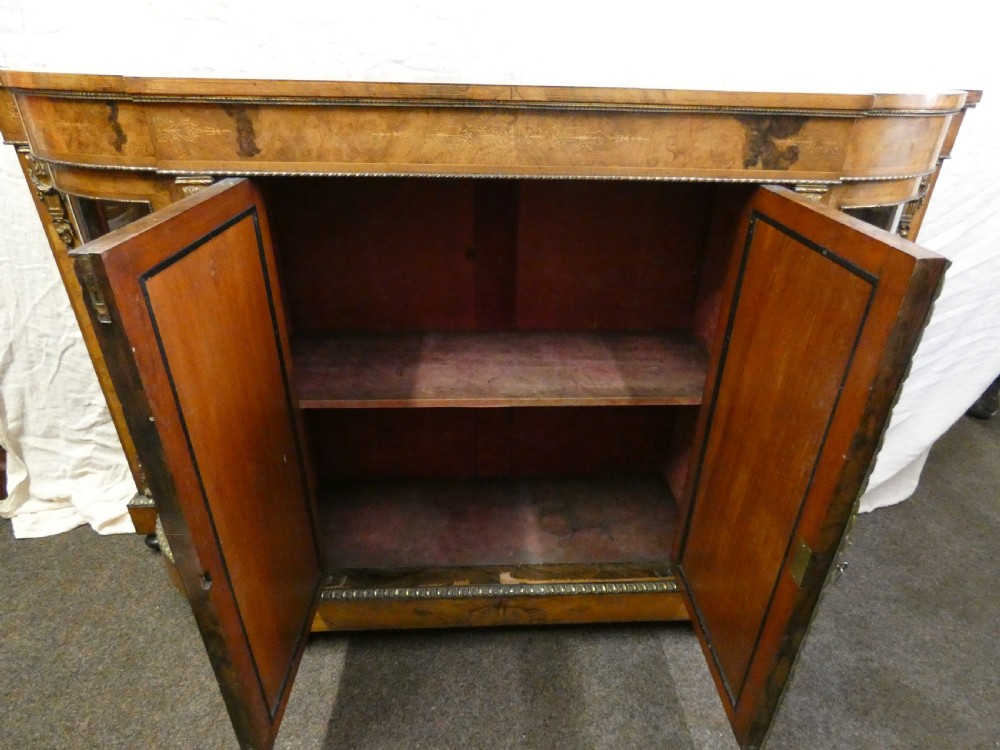 A Victorian burr walnut credenza featuring central wooden doors with marquetry urn motifs, flanked by curved glazed side compartments and gilt bronze mounts. View IX