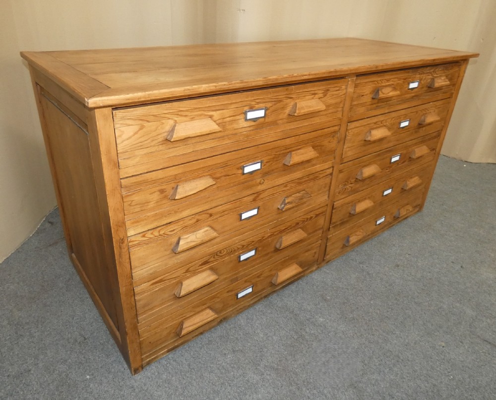 A wide pine cabinet featuring ten shallow drawers in two columns, each fitted with angular wooden handles and metal label holders. View VIII