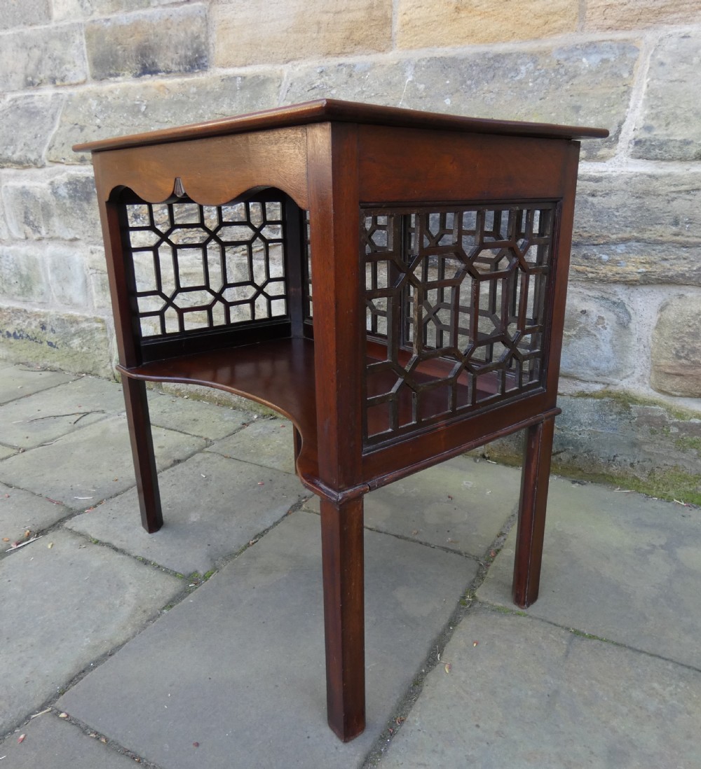 A dark mahogany side table featuring decorative geometric fretwork panels and a curved lower shelf. View IV