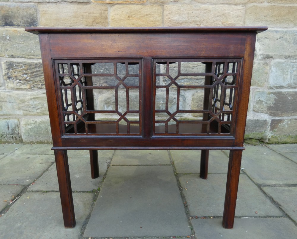 A dark mahogany side table featuring decorative geometric fretwork panels and a curved lower shelf. View VI