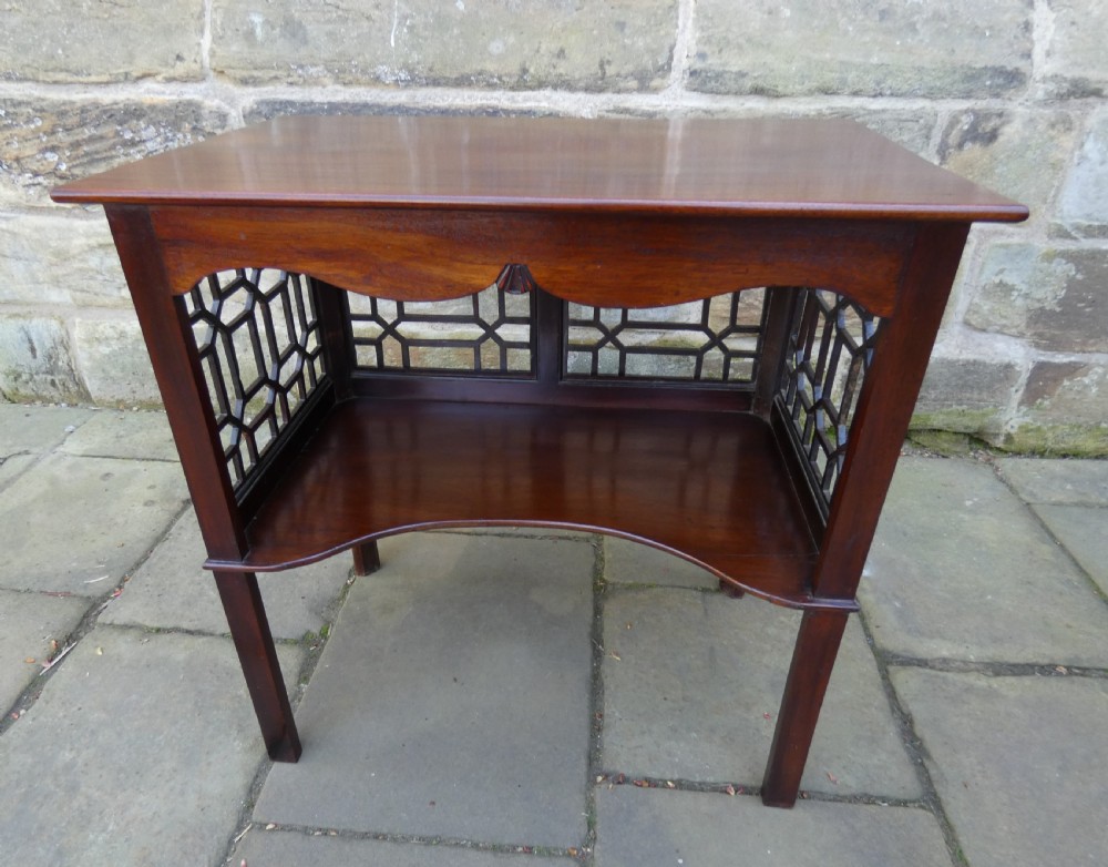 A dark mahogany side table featuring decorative geometric fretwork panels and a curved lower shelf. View VII