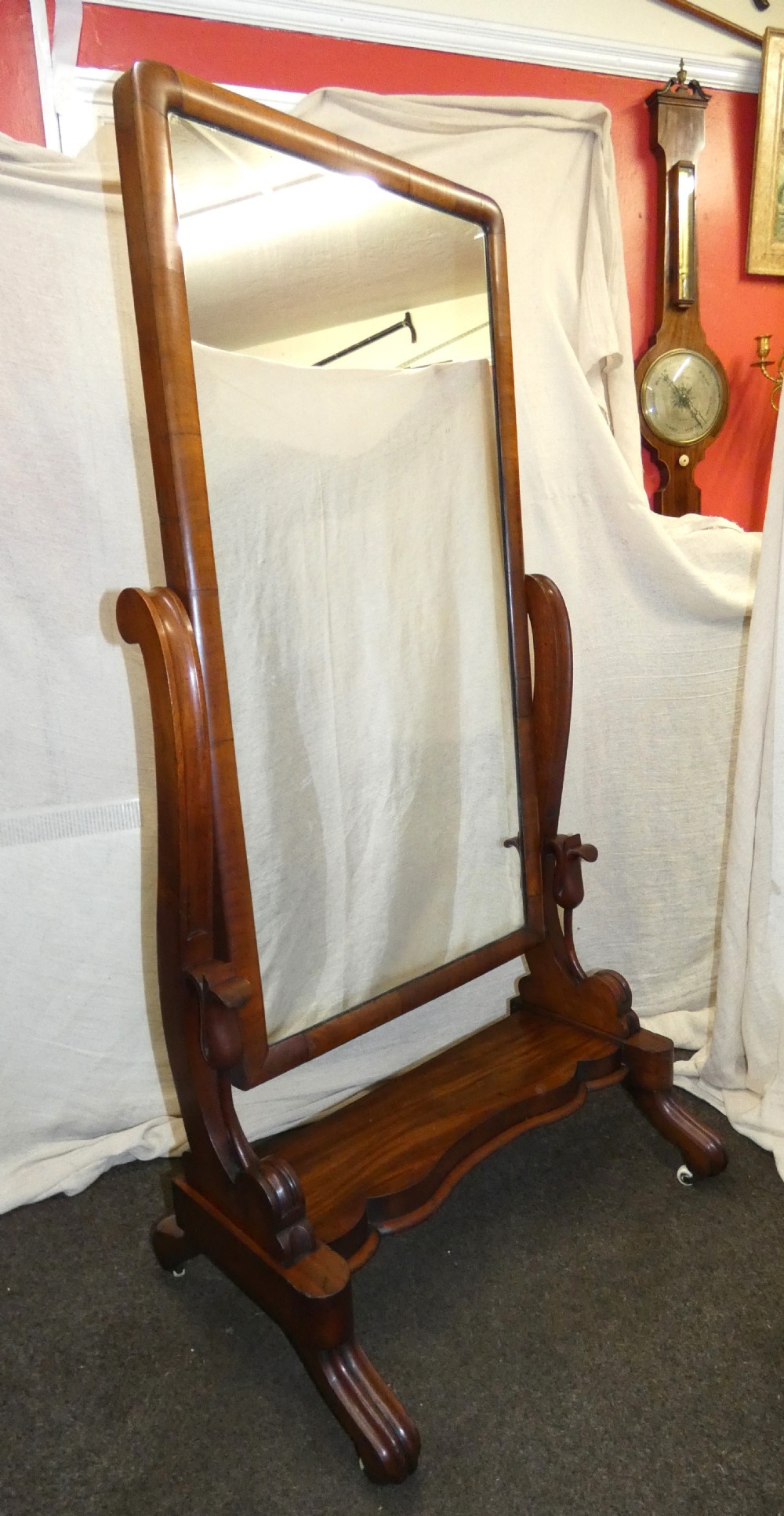 A freestanding Victorian mahogany cheval mirror featuring a rounded rectangular glass frame held by curved uprights above a serpentine base platform with splayed legs. View II