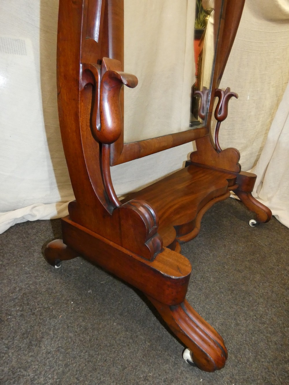 A freestanding Victorian mahogany cheval mirror featuring a rounded rectangular glass frame held by curved uprights above a serpentine base platform with splayed legs. View III
