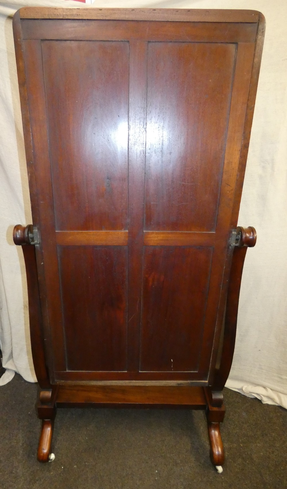 A freestanding Victorian mahogany cheval mirror featuring a rounded rectangular glass frame held by curved uprights above a serpentine base platform with splayed legs. View VII