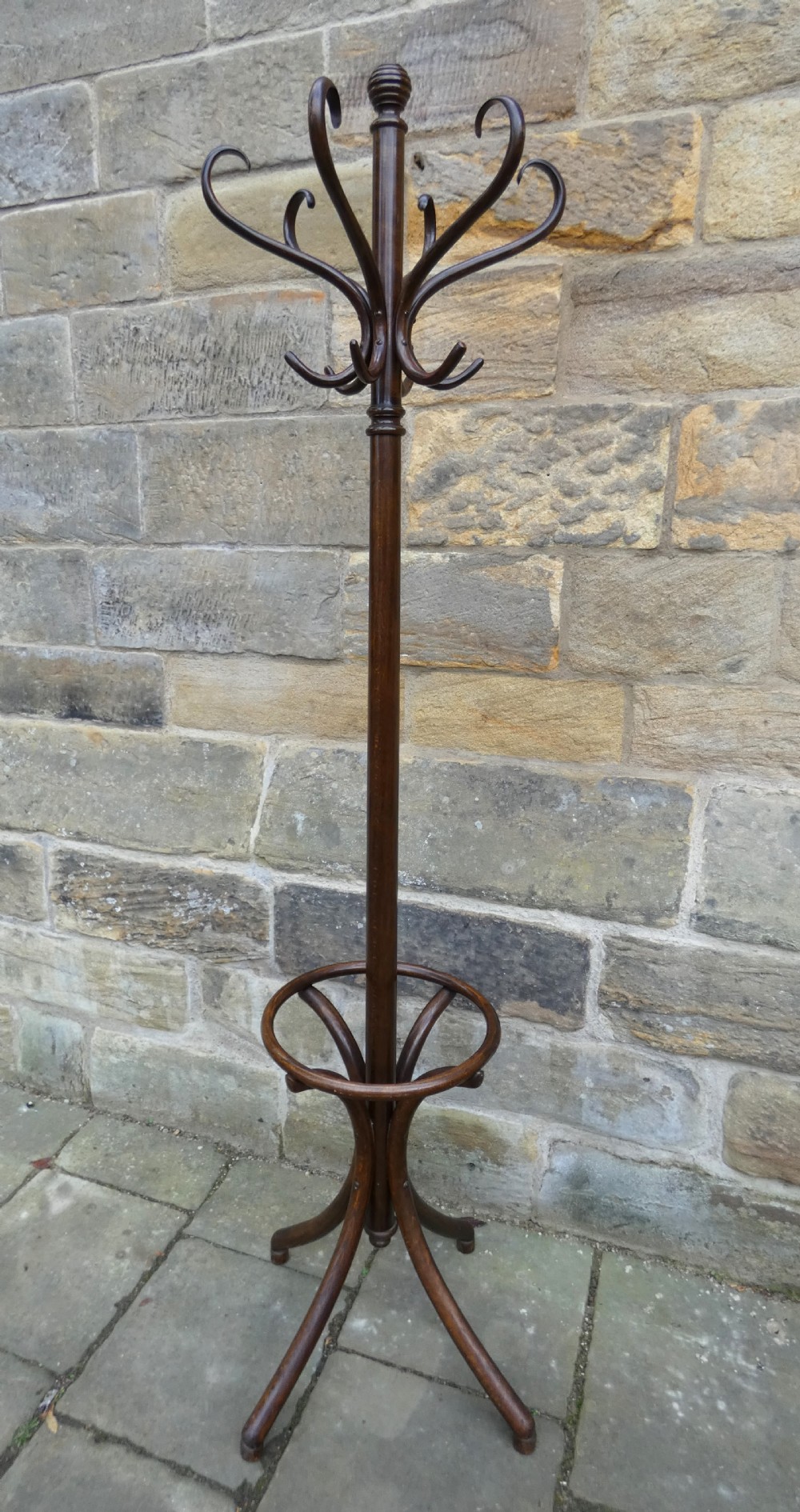 A dark brown steam-bent beechwood coat stand featuring a revolving top with double scrolled hooks, an umbrella ring, and a four-legged splayed base.