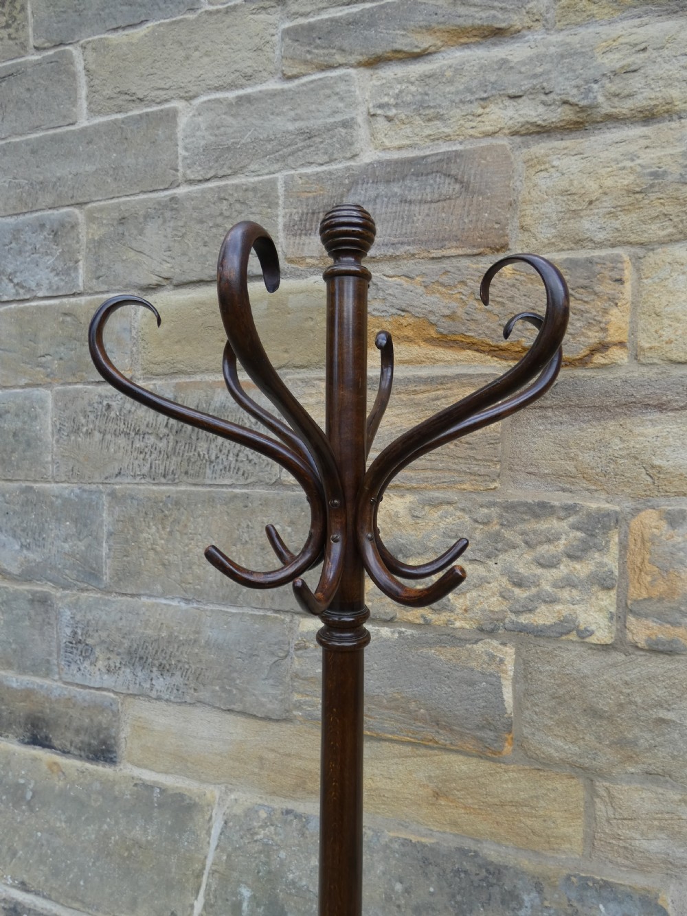 A dark brown steam-bent beechwood coat stand featuring a revolving top with double scrolled hooks, an umbrella ring, and a four-legged splayed base. View II