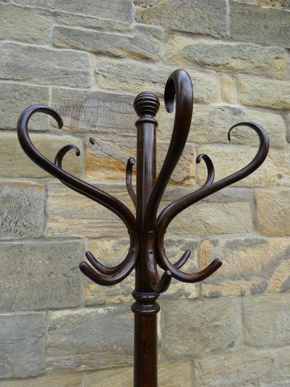 A dark brown steam-bent beechwood coat stand featuring a revolving top with double scrolled hooks, an umbrella ring, and a four-legged splayed base. View III