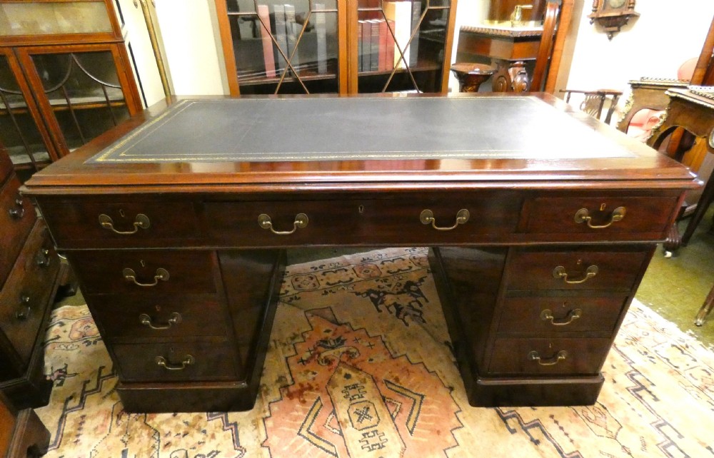 An antique mahogany partners desk featuring a dark leather writing surface, multiple pedestal drawers, and brass swan-neck handles. View II