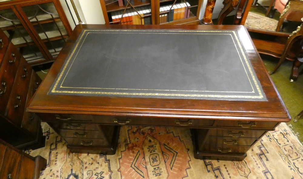 An antique mahogany partners desk featuring a dark leather writing surface, multiple pedestal drawers, and brass swan-neck handles. View IV
