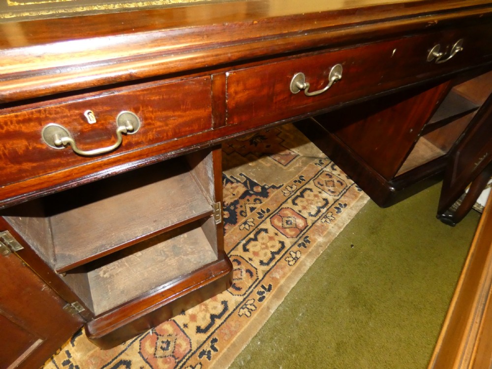 An antique mahogany partners desk featuring a dark leather writing surface, multiple pedestal drawers, and brass swan-neck handles. View VII