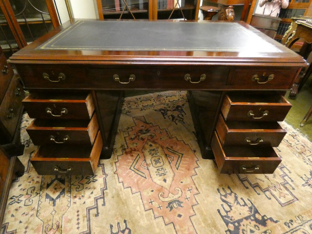 An antique mahogany partners desk featuring a dark leather writing surface, multiple pedestal drawers, and brass swan-neck handles. View VIII