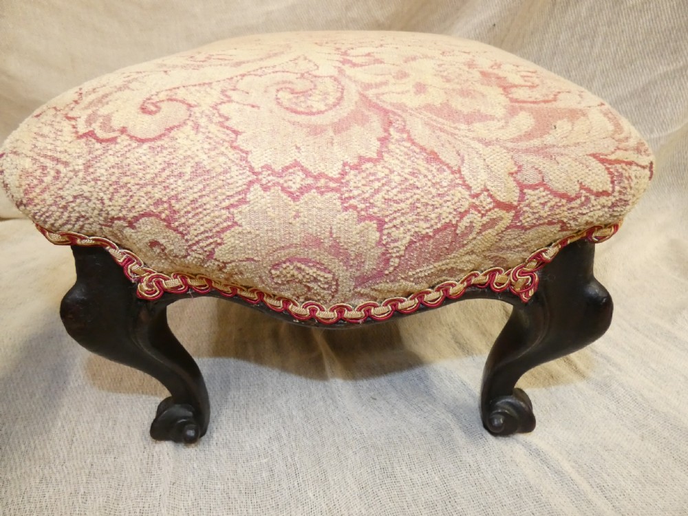 A pair of low antique footstools featuring carved dark wood cabriole legs and gold damask pattern fabric upholstery. View IV