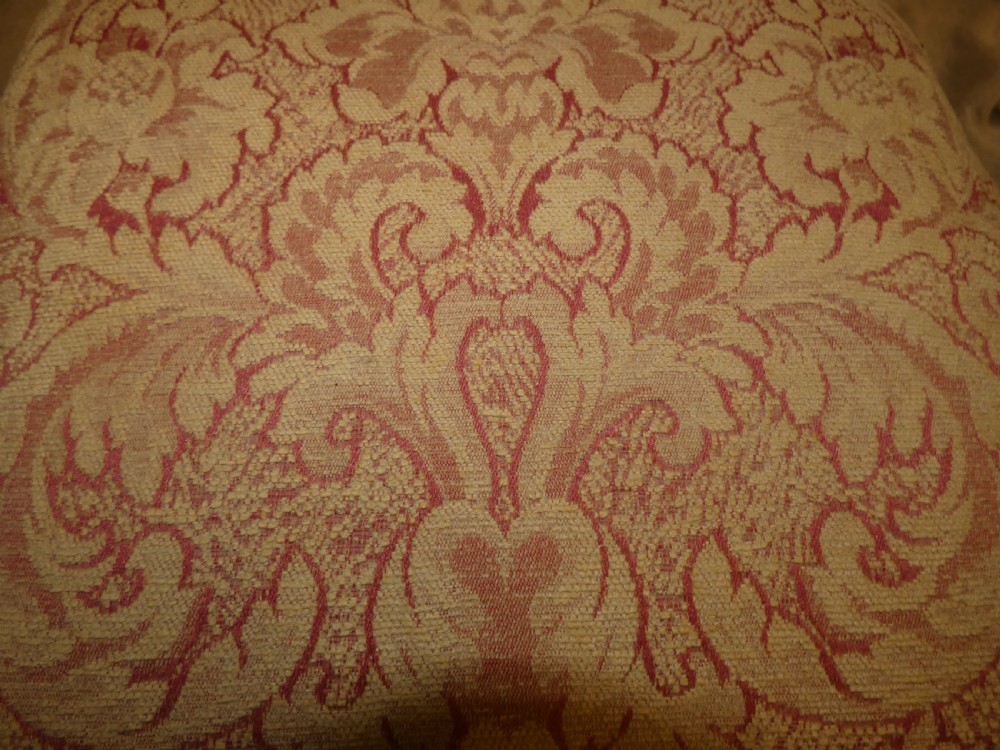 A pair of low antique footstools featuring carved dark wood cabriole legs and gold damask pattern fabric upholstery. View V