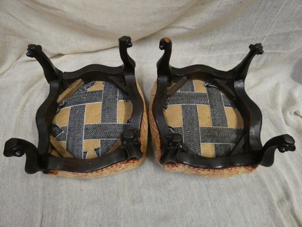A pair of low antique footstools featuring carved dark wood cabriole legs and gold damask pattern fabric upholstery. View VII