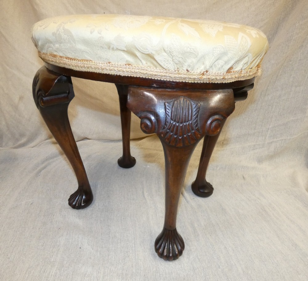 An oval upholstered antique dressing stool featuring cream damask fabric and dark mahogany cabriole legs with carved ball and claw feet. View V