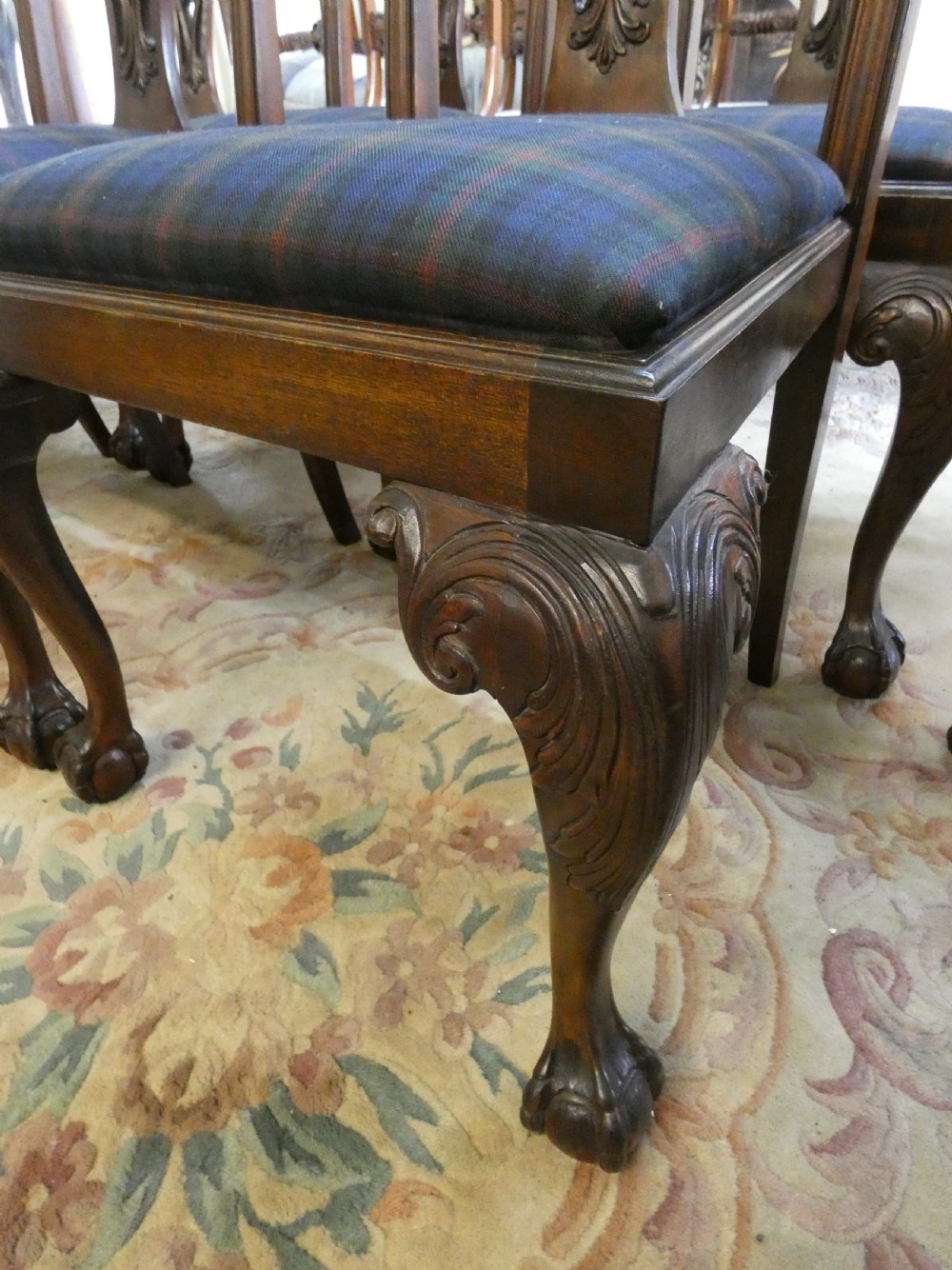 A set of eight dark mahogany Chippendale style dining chairs featuring carved pierced splats, cabriole legs with ball and claw feet, and blue tartan upholstered seats. View III