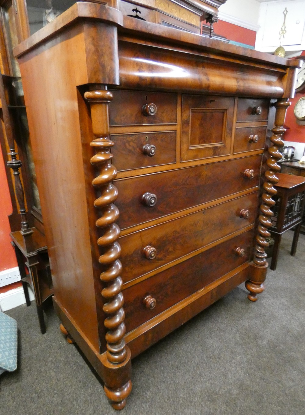 A tall Victorian flame mahogany Scotch chest of drawers featuring spiral barley twist side columns, a central square drawer flanked by smaller drawers, and three long graduated drawers below. View II