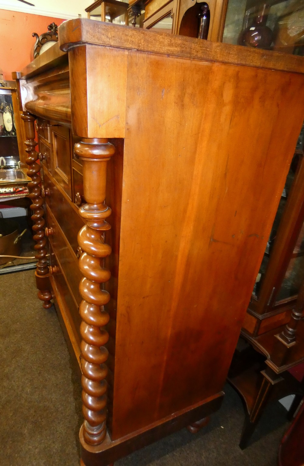 A tall Victorian flame mahogany Scotch chest of drawers featuring spiral barley twist side columns, a central square drawer flanked by smaller drawers, and three long graduated drawers below. View V