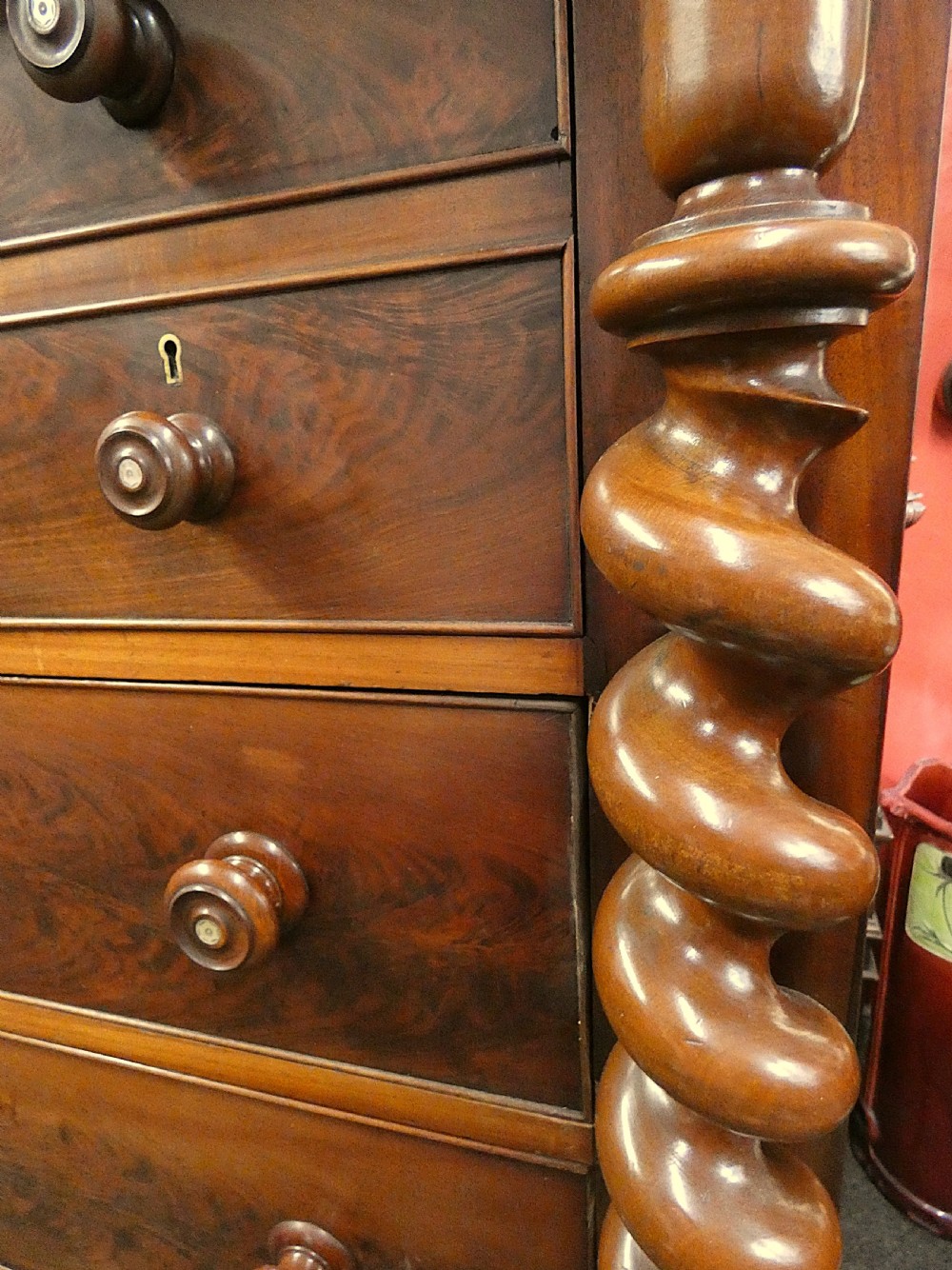 A tall Victorian flame mahogany Scotch chest of drawers featuring spiral barley twist side columns, a central square drawer flanked by smaller drawers, and three long graduated drawers below. View VI