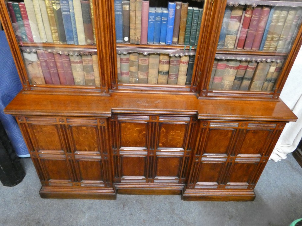 A large three-section antique oak bookcase featuring glazed upper doors above panelled lower cupboards. View V
