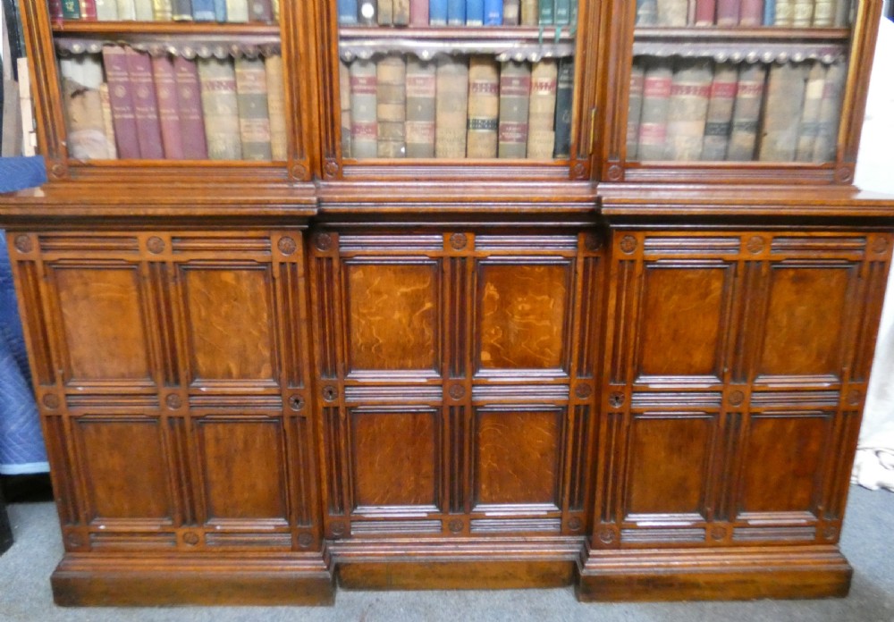 A large three-section antique oak bookcase featuring glazed upper doors above panelled lower cupboards. View VI